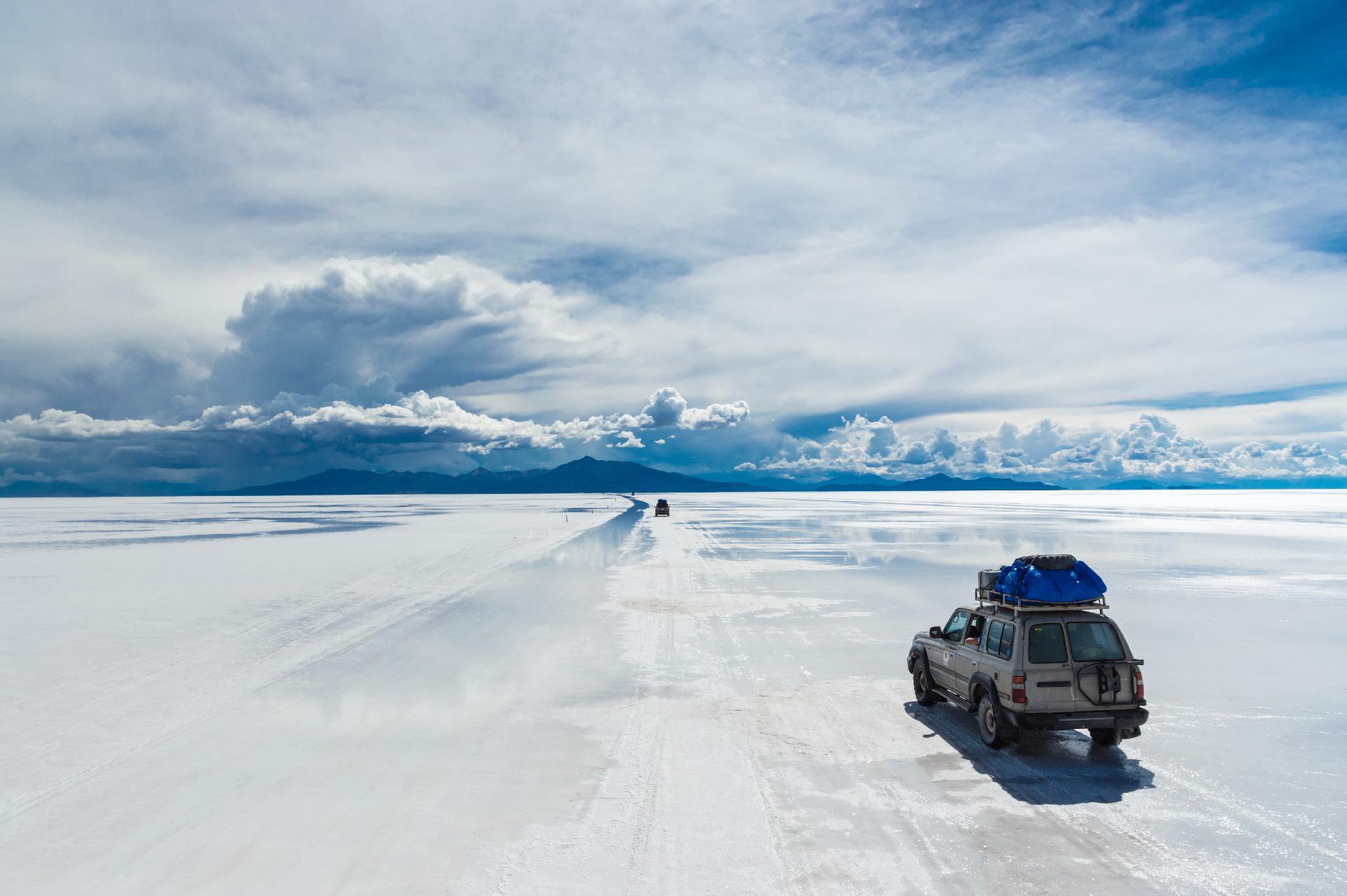 Bolivia, varios vehículos todo terreno conduciendo por Salar de Uyuni